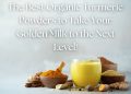 Glass of golden milk with bowls of turmeric powder, fresh turmeric roots, cinnamon sticks, and spices on a soft background.